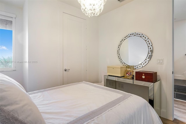 bedroom featuring an inviting chandelier and wood finished floors