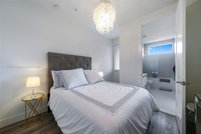 bedroom featuring baseboards, a chandelier, wood finished floors, and connected bathroom