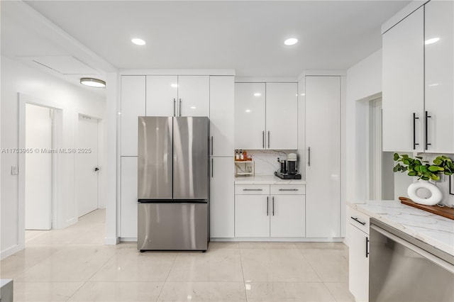 kitchen with white cabinets, modern cabinets, appliances with stainless steel finishes, light stone countertops, and backsplash