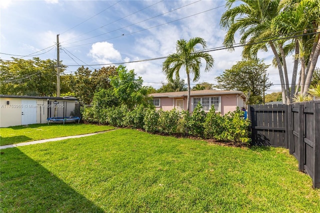 view of yard featuring a trampoline and fence