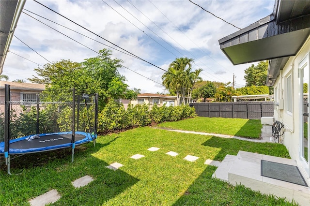 view of yard with a trampoline and fence