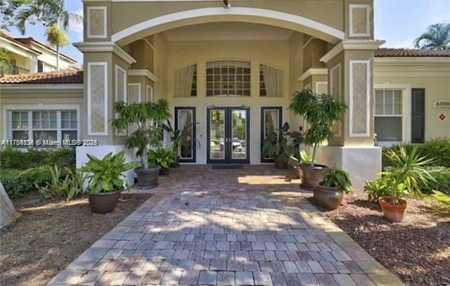 view of exterior entry featuring french doors, a tile roof, and stucco siding