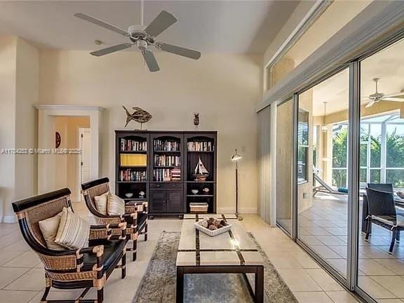 sitting room with light tile patterned floors, ceiling fan, a high ceiling, and baseboards