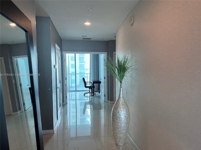 hall featuring light tile patterned floors, visible vents, and baseboards