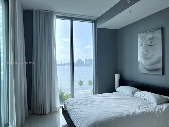 bedroom featuring a city view, a water view, and tile patterned floors