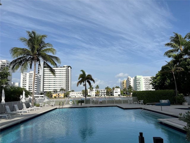 community pool with a view of city, fence, and a patio