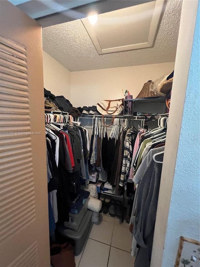 spacious closet featuring attic access and tile patterned flooring