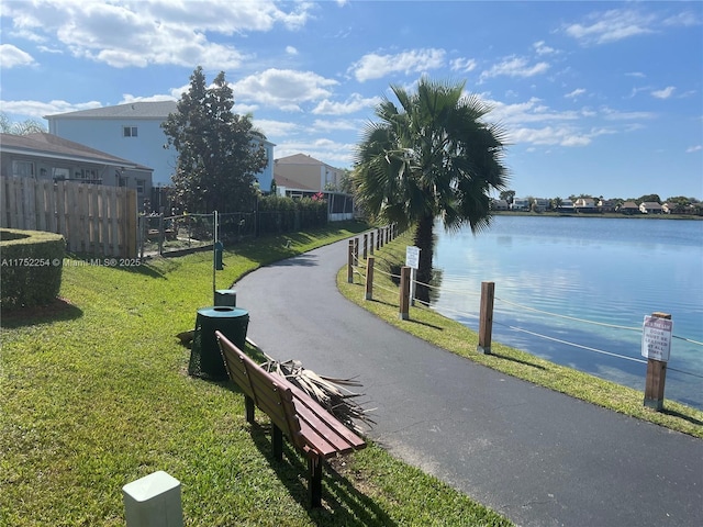 surrounding community with a water view, a yard, and fence