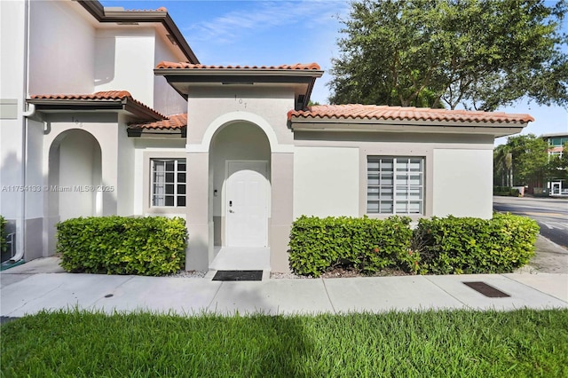 view of exterior entry with a tile roof and stucco siding