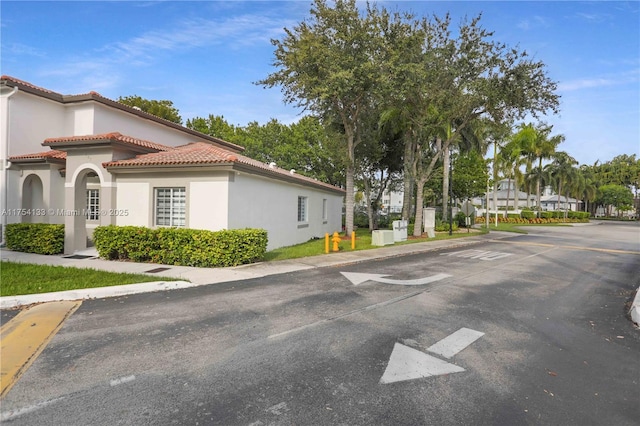 view of property exterior with a tile roof and stucco siding