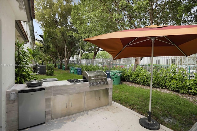 view of patio / terrace featuring exterior kitchen, a grill, and fence