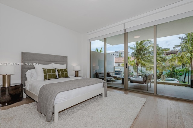 bedroom with access to exterior, hardwood / wood-style flooring, and floor to ceiling windows