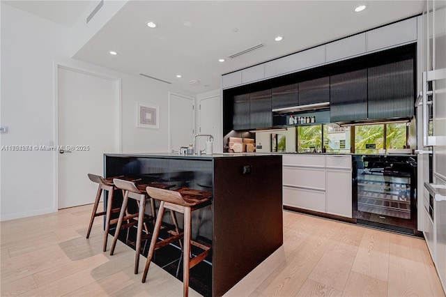 bar with light wood-style floors, wine cooler, a sink, and recessed lighting