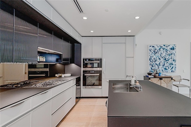 kitchen featuring dark countertops, visible vents, appliances with stainless steel finishes, white cabinetry, and a sink