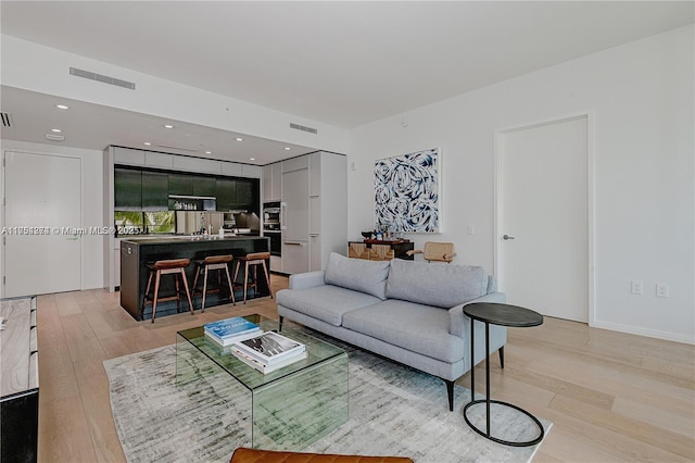 living area featuring light wood-type flooring, visible vents, and recessed lighting