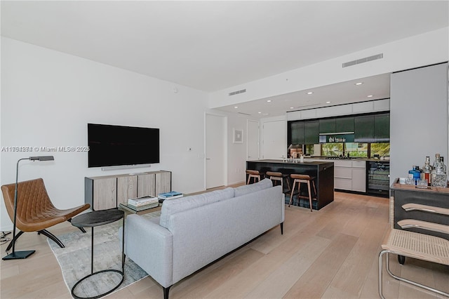 living area featuring light wood-style flooring, wine cooler, visible vents, and recessed lighting