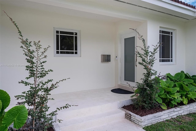 doorway to property featuring stucco siding