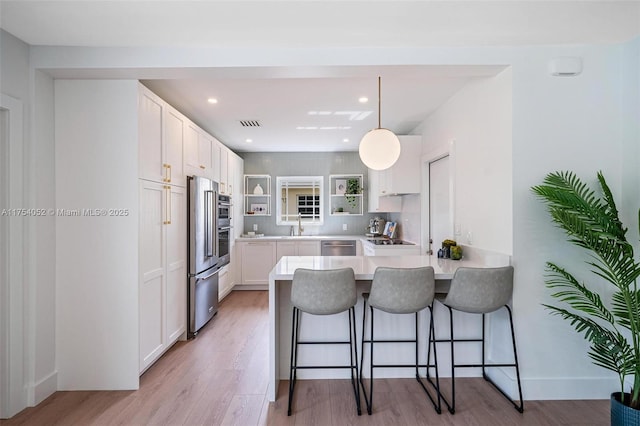 kitchen with a kitchen bar, open shelves, light wood finished floors, white cabinets, and a peninsula