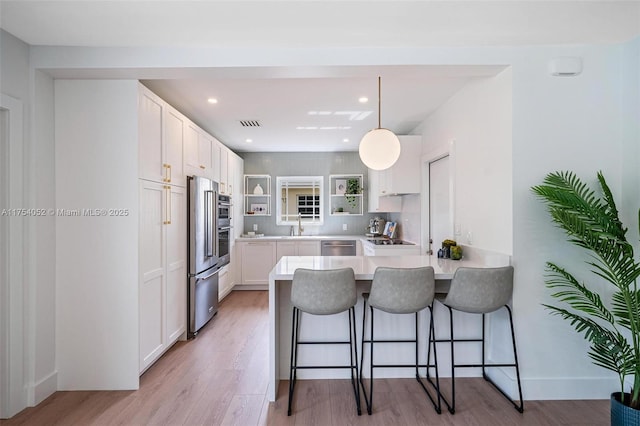 kitchen featuring a peninsula, light wood-type flooring, a kitchen bar, white cabinetry, and open shelves