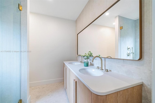 bathroom featuring baseboards, double vanity, and a sink