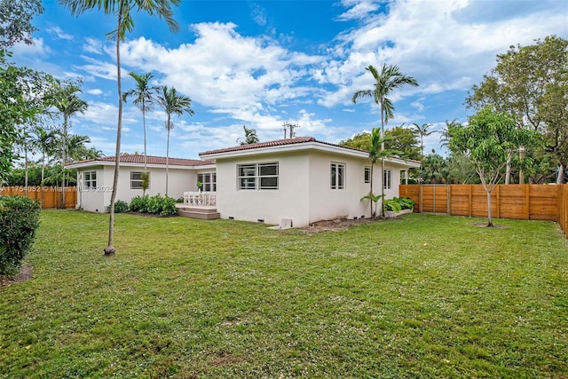 rear view of house with a fenced backyard, a wooden deck, a lawn, and stucco siding