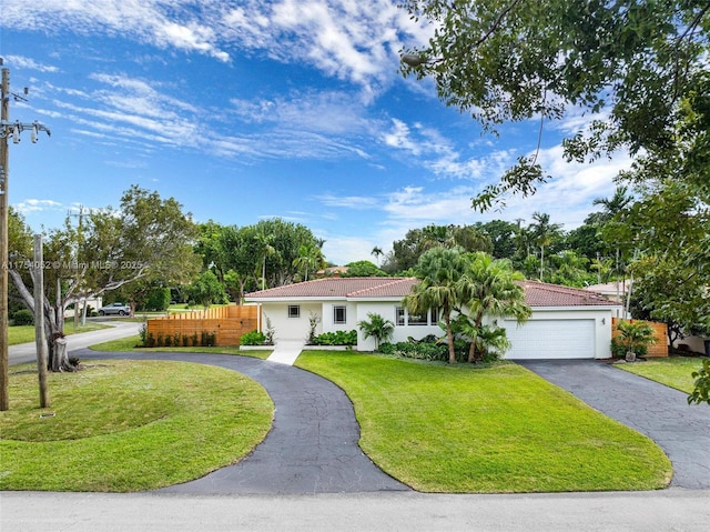 view of front of property featuring driveway, stucco siding, an attached garage, a front lawn, and a tiled roof