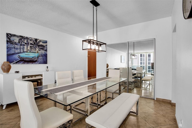 dining area with tile patterned flooring, a textured ceiling, baseboards, and an inviting chandelier