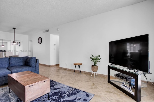 living room featuring baseboards, visible vents, a textured ceiling, and tile patterned floors