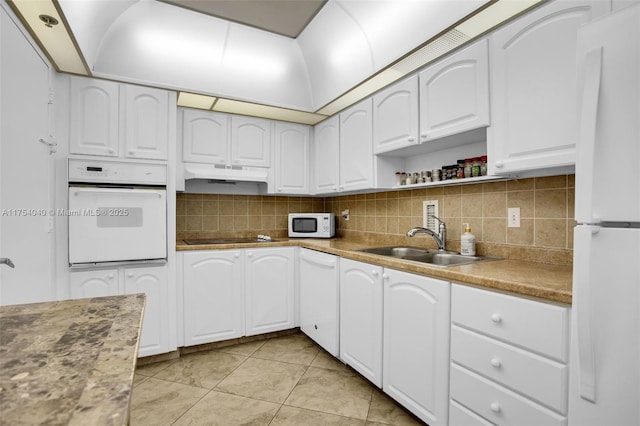 kitchen featuring white appliances, a sink, under cabinet range hood, and decorative backsplash