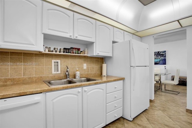 kitchen with light tile patterned floors, backsplash, white cabinetry, a sink, and white appliances