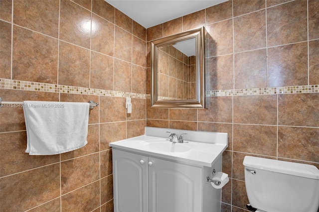 bathroom featuring toilet, vanity, and tile walls