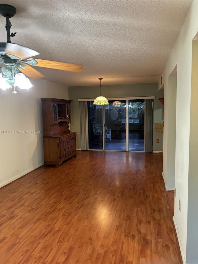 unfurnished living room featuring a textured ceiling, wood finished floors, a ceiling fan, and baseboards