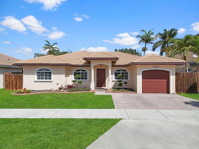 mediterranean / spanish-style house featuring an attached garage, decorative driveway, a front yard, and fence