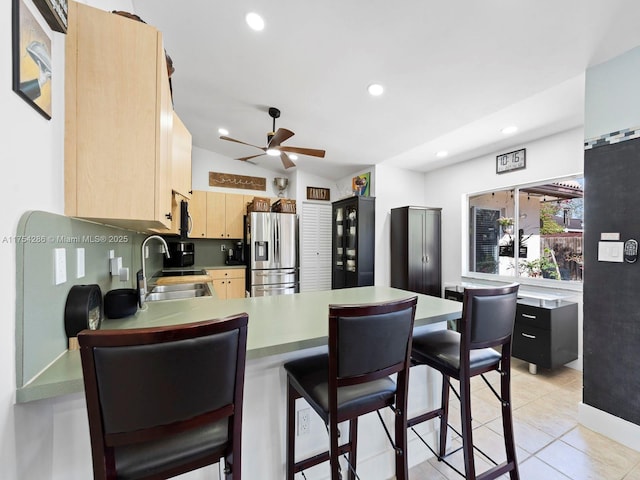 kitchen with stainless steel refrigerator with ice dispenser, recessed lighting, light brown cabinetry, a sink, and a peninsula