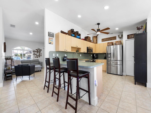 kitchen featuring light tile patterned floors, light brown cabinets, a peninsula, visible vents, and appliances with stainless steel finishes