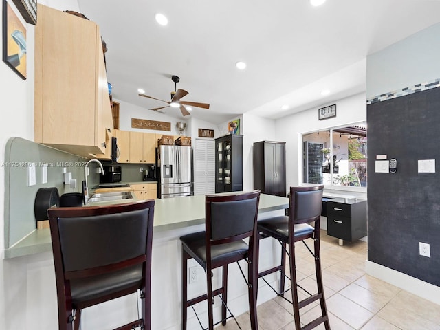 kitchen with light countertops, light brown cabinets, a sink, a peninsula, and stainless steel fridge with ice dispenser