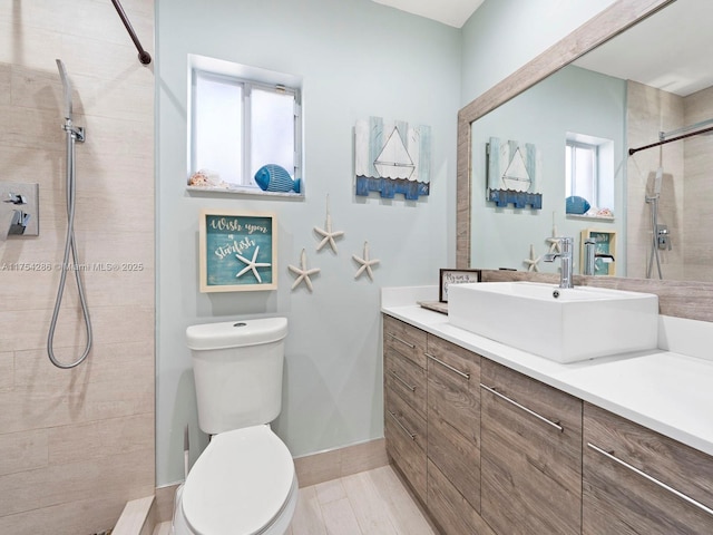 full bath featuring toilet, a tile shower, and vanity