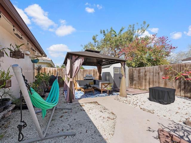 view of patio / terrace featuring a storage shed, a fenced backyard, an outbuilding, a gazebo, and an outdoor living space