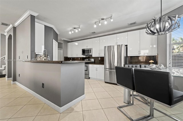 kitchen with light tile patterned floors, stainless steel appliances, visible vents, dark countertops, and crown molding