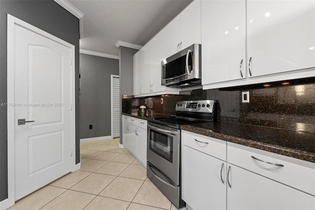 kitchen featuring crown molding, light tile patterned floors, backsplash, appliances with stainless steel finishes, and white cabinets