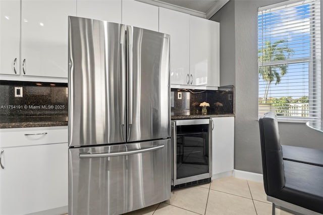 kitchen featuring light tile patterned floors, wine cooler, white cabinets, freestanding refrigerator, and decorative backsplash