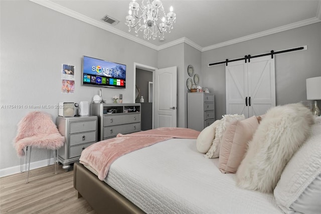 bedroom featuring a barn door, visible vents, baseboards, light wood finished floors, and crown molding