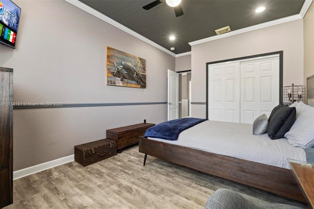 bedroom featuring a closet, ornamental molding, ceiling fan, wood finished floors, and baseboards