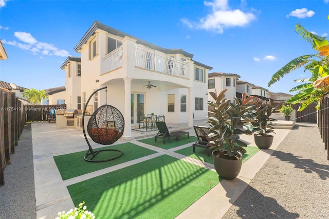 rear view of house with a balcony, a fenced backyard, ceiling fan, a patio area, and stucco siding