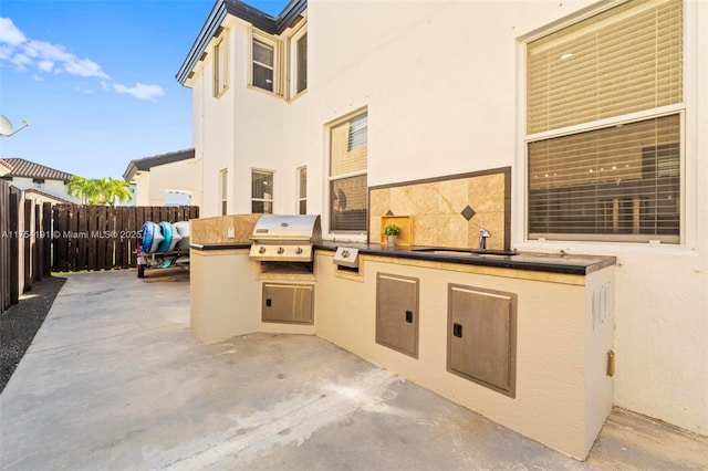 view of patio / terrace featuring a sink, an outdoor kitchen, area for grilling, and fence