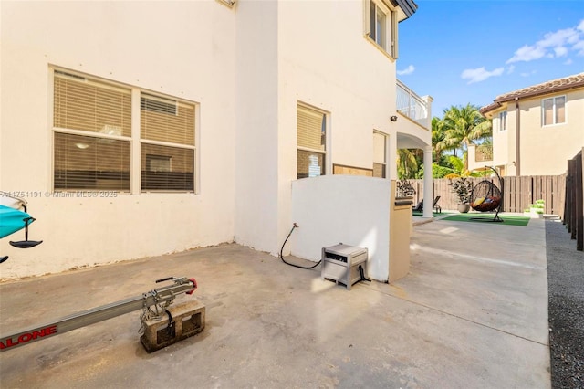 view of patio with fence and a balcony