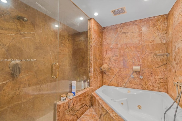 bathroom featuring a jetted tub, tile walls, visible vents, and tiled shower