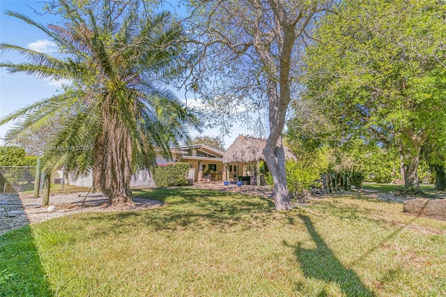 view of property hidden behind natural elements with a front lawn and fence