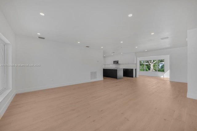 unfurnished living room featuring light wood-type flooring, baseboards, visible vents, and recessed lighting