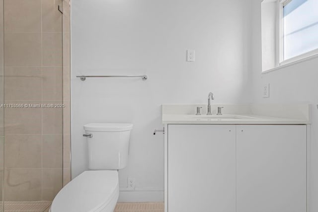 bathroom featuring toilet, tiled shower, and vanity